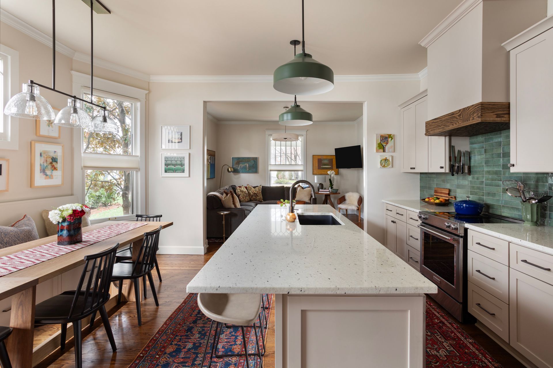 Remodelled kitchen with a long speckled stone island, green tile backsplash and a timber range hood