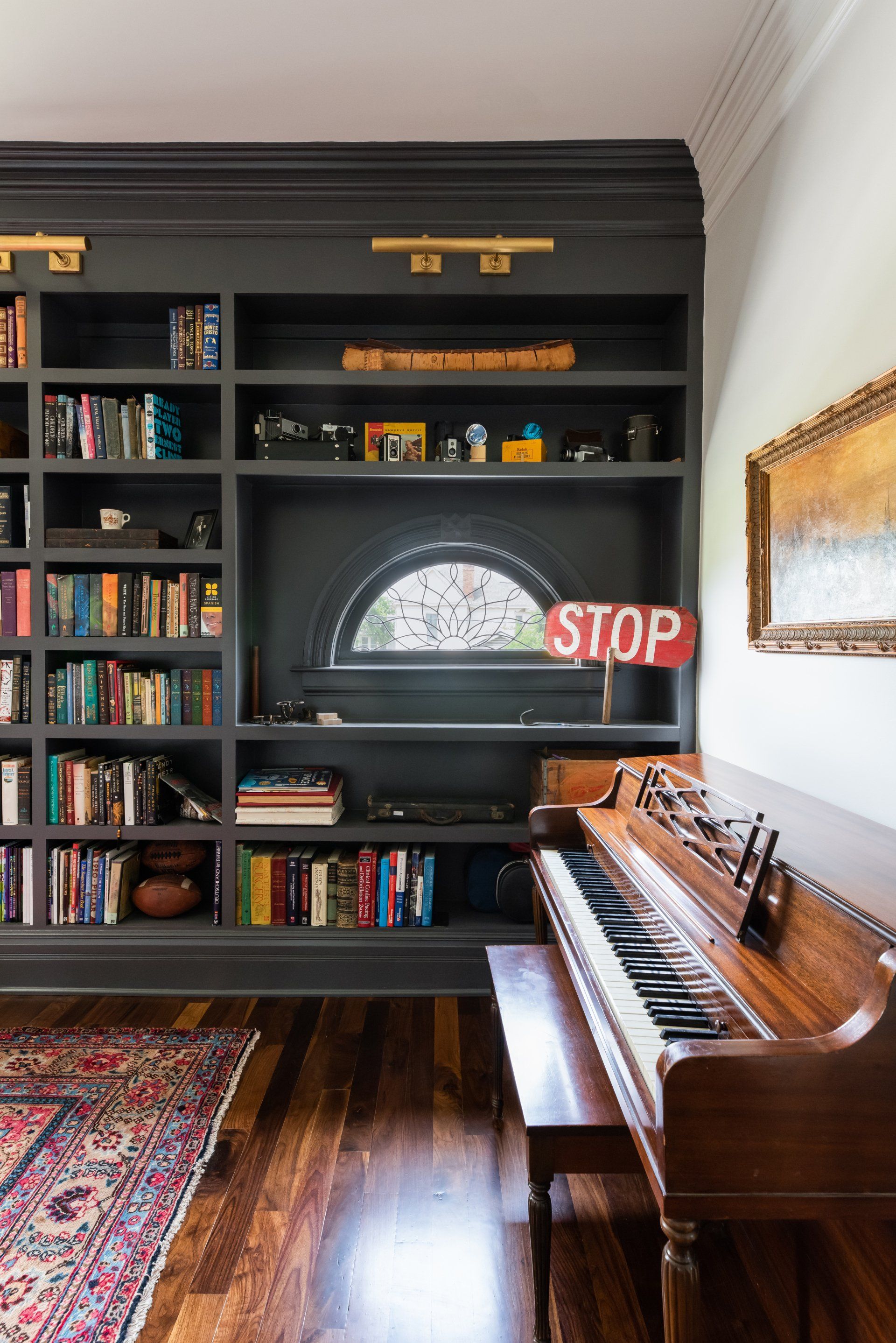 Charcoal built-in library shelving beside an upright piano in a restored Nashville home