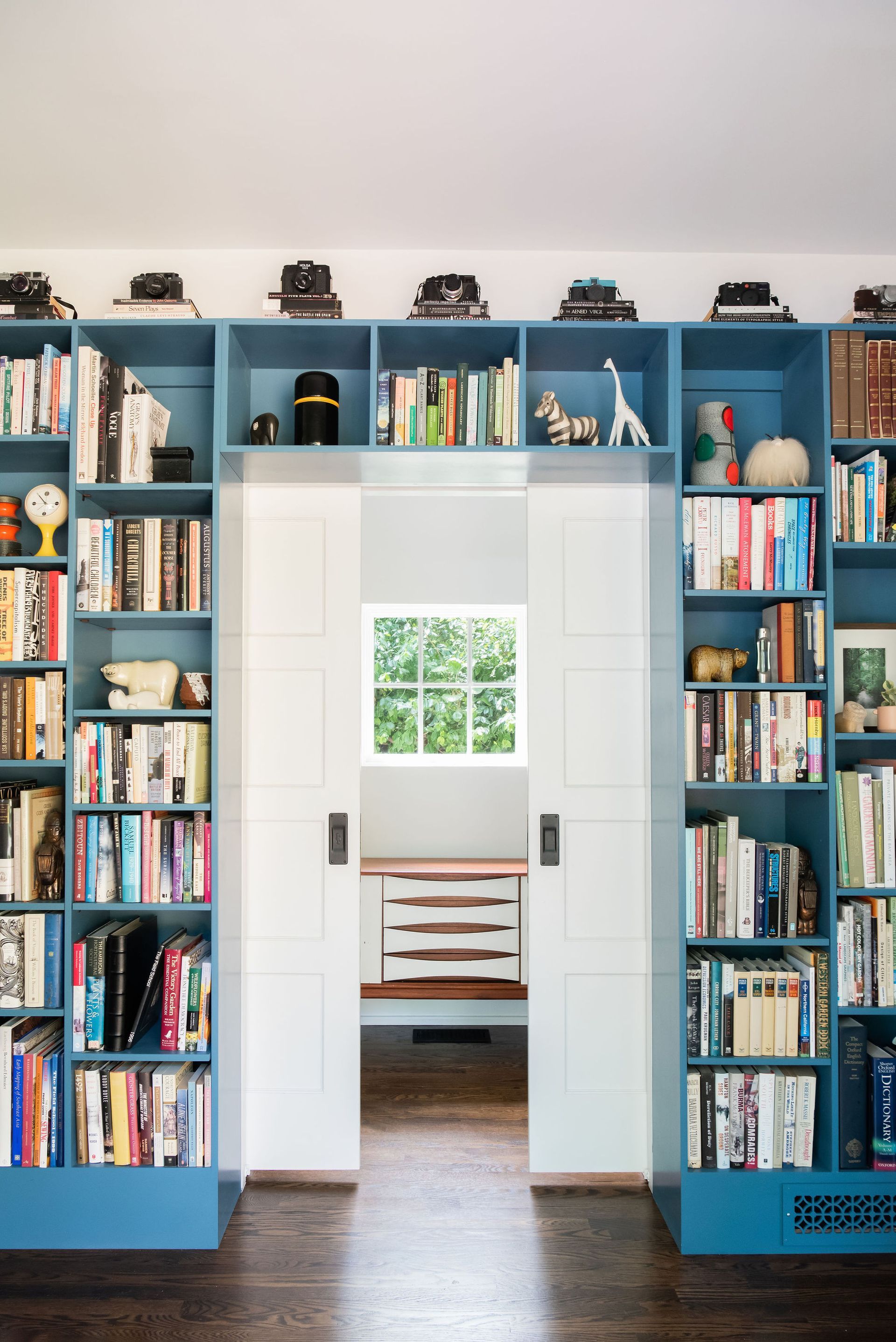 Blue built-in library shelving flanking a pair of pocket doors